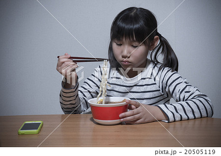 カップラーメンを寂しく食べる女の子の写真素材