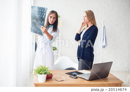 Woman doctor and patient in hospital looking at x 20514674