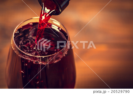 Pouring red wine into the glass against wooden  20529790