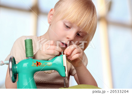 Girl sew on a children's sewing machine. 20533204
