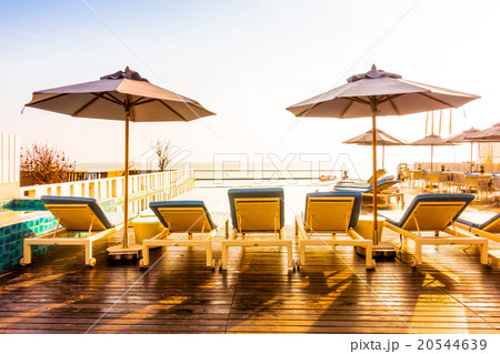 Umbrella and chair around swimming pool 20544639