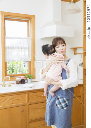 キッチンで赤ちゃんを抱っこするお母さん キッチンで赤ちゃんを抱っこするお母さん 20552974