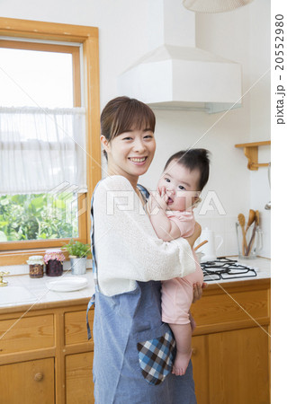 キッチンで赤ちゃんを抱っこするお母さん 20552980