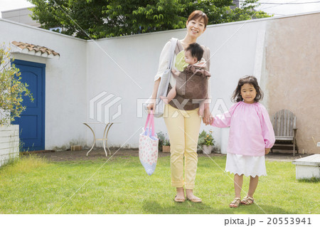 外を歩く赤ちゃんを抱っこしているお母さんと女の子 20553941