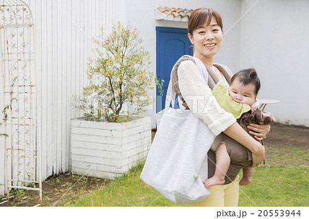 外を歩く赤ちゃんを抱っこしているお母さんの写真素材
