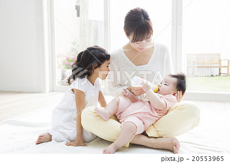 赤ちゃんにミルクをあげるお母さんと女の子 20553965
