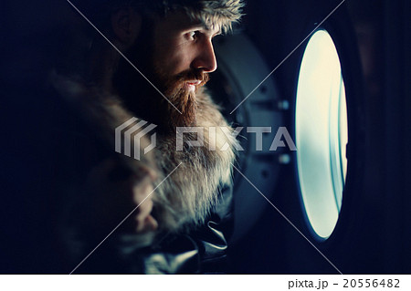 man looking through a porthole of a ship 20556482