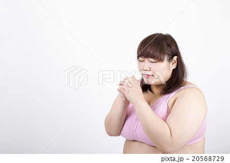 白い背景の前で目を閉じて祈っている太った若い女性 白い背景の前で目を閉じて祈っている太った若い女性 20568729