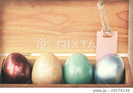 Colorful easter eggs in wooden box with paper tag. 20574130