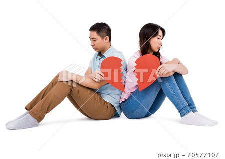Sad couple holding broken heart pieces Sad couple holding broken heart pieces 20577102