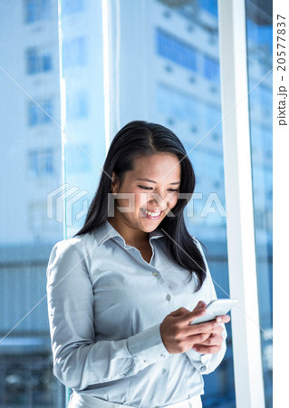 Smiling businesswoman using smartphone 20577837