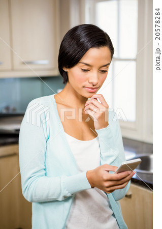 Thoughtful brunette using smartphone 20578284