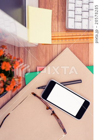 Smartphone and eye glasses on paper by computer at desk 20578285