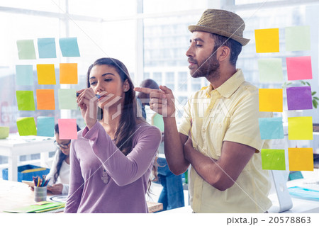 Businessman pointing while businesswoman writing on adhesive not Businessman pointing while businesswoman writing on adhesive not 20578863