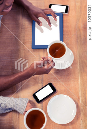 Colleagues holding coffee cups while using technologies Colleagues holding coffee cups while using technologies 20579034