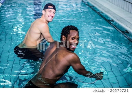Fit men cycling in the pool Fit men cycling in the pool 20579721