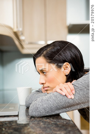 Thoughtful brunette looking at laptop 20579976