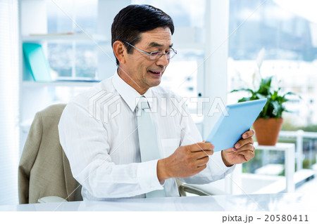 Smiling asian businessman using tablet 20580411