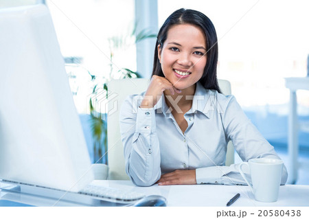 Smiling businesswoman with chin on fist 20580438