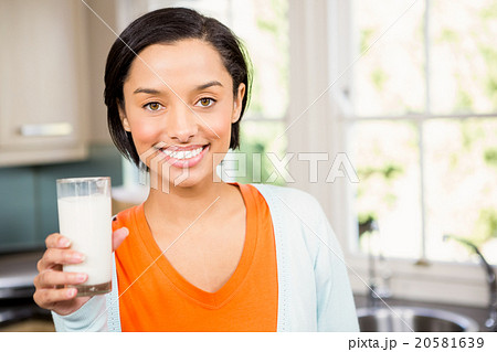 Happy brunette holding glass of milk 20581639