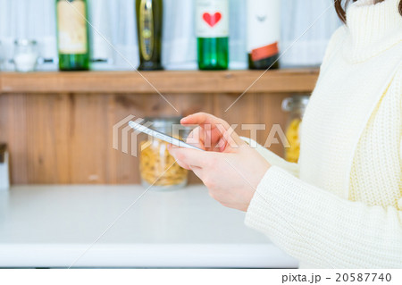 台所でスマホを操作する女性の手元　白い　台所　キッチン　調理場　レシピ検索　メニュー検索 20587740
