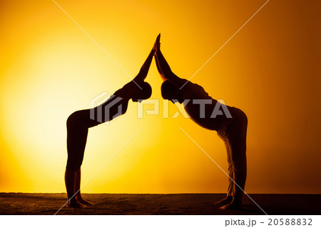 Two people practicing yoga in the sunset light Two people practicing yoga in the sunset light 20588832