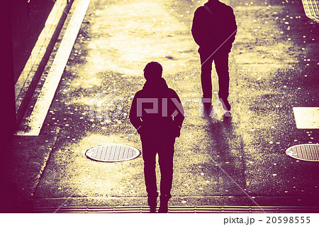 歩道を歩く人の影 後ろ姿の写真素材