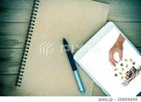 Notebook with tablet show the Hand holding and adding a coin on Notebook with tablet show the Hand holding and adding a coin on 20609848