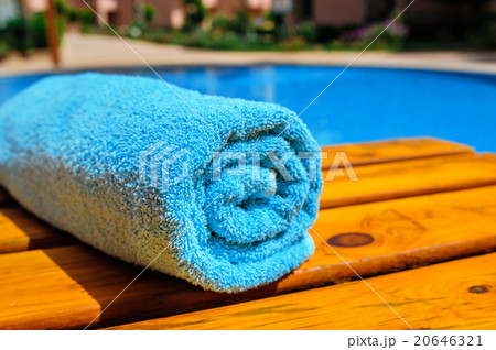 blue rolled-up towel lying on a lounger near pool blue rolled-up towel lying on a lounger near pool 20646321
