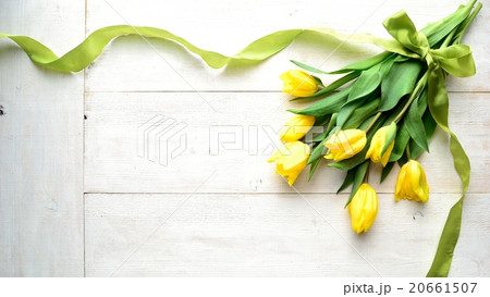 黄色いチューリップの花束 白木材背景の写真素材