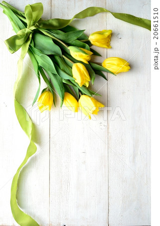 黄色いチューリップの花束 白木材背景の写真素材