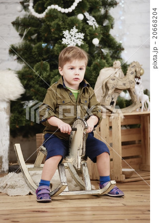 boy ride wooden horse in front christmas tree 20668204