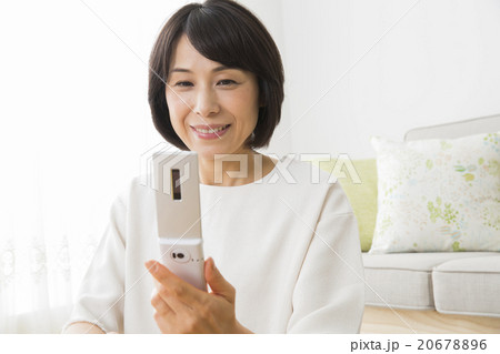 リビングで携帯電話を使う40代女性 リビングで携帯電話を使う40代女性 20678896