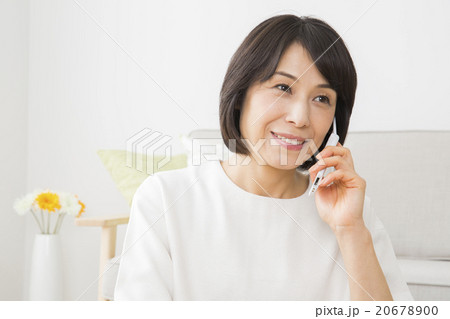 リビングで携帯電話を使う40代女性 20678900