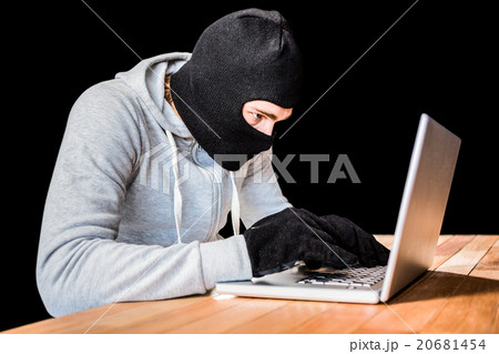 Focused thief with hood typing on laptop Focused thief with hood typing on laptop 20681454