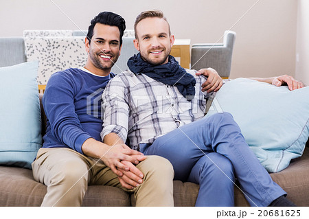 Gay couple holding hands on couch Gay couple holding hands on couch 20681625