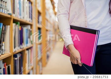 Female student holding textbooks in library 20681753