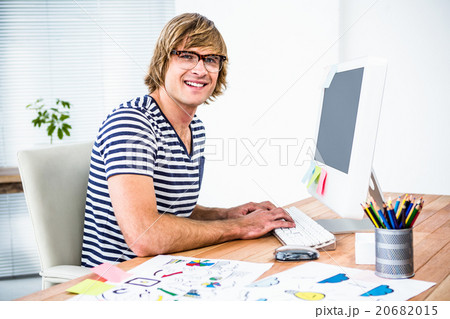 Smiling hipster businessman using his computer Smiling hipster businessman using his computer 20682015
