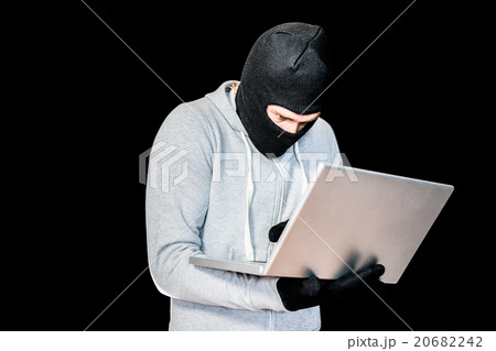 Focused thief with hood typing on laptop Focused thief with hood typing on laptop 20682242