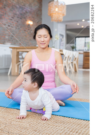 Calm mother meditating on mat at home Calm mother meditating on mat at home 20682264