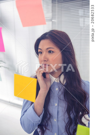 Asian businesswoman using sticky notes on wall 20682533