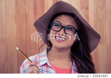 Smiling Asian woman with hat holding pencil 20682887