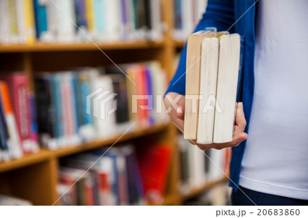 Happy female student taking books in the library Happy female student taking books in the library 20683860