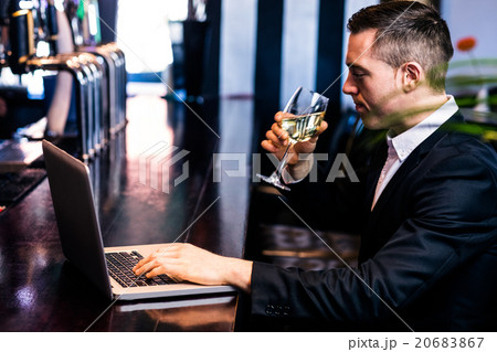 Businessman getting a glass of wine and using laptop 20683867