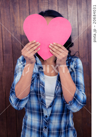 Woman hiding her face behind paper heart 20684031