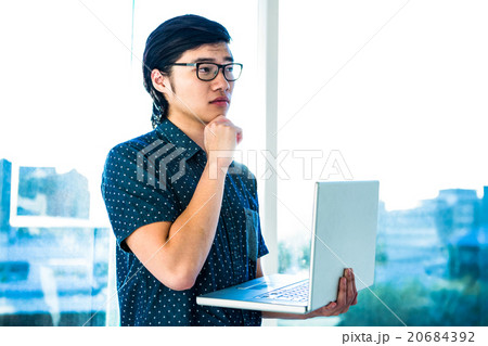 Thoughtful hipster using his laptop Thoughtful hipster using his laptop 20684392