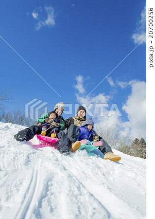 雪の丘でソリ遊びをする4人家族 20700256