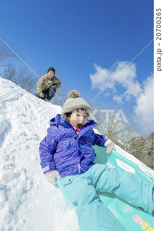 雪の丘でソリ遊びをする父と娘 20700265
