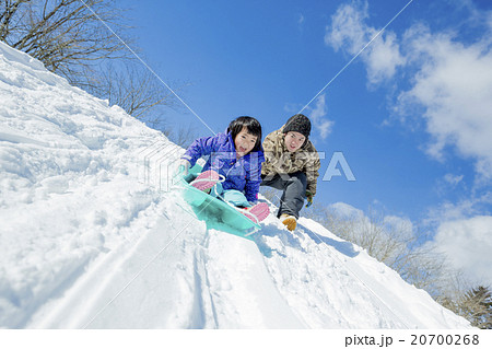雪の丘でソリ遊びをする父と娘 20700268