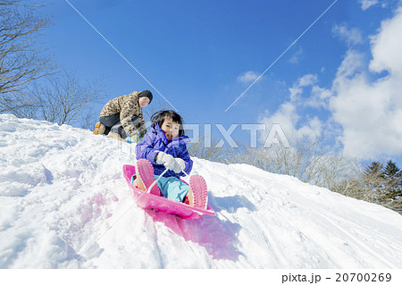 雪の丘でソリ遊びをする父と娘 20700269